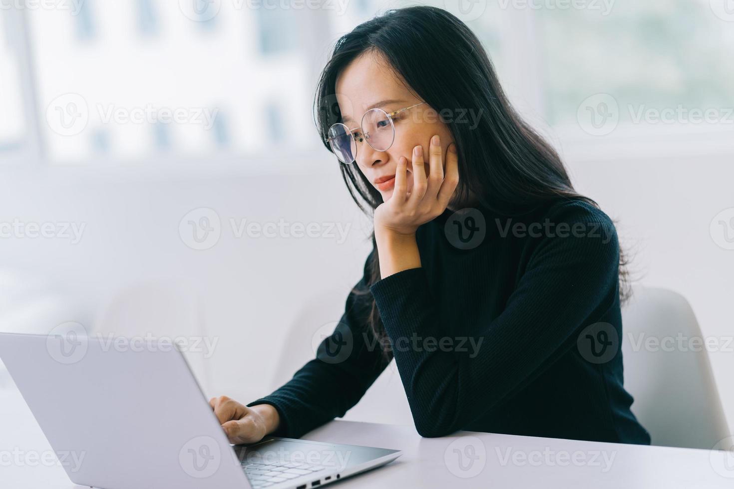 ung asiatisk kvinna som använder bärbara datorn på kontoret foto