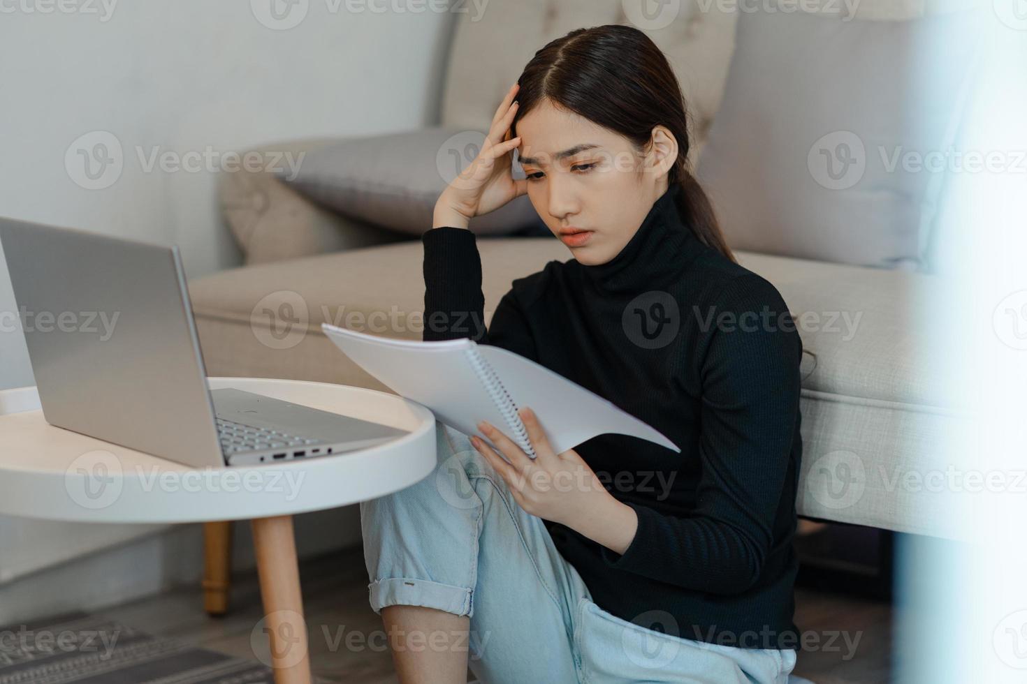 vacker asiatisk kvinna som sitter och beräknar inkomstskatt foto