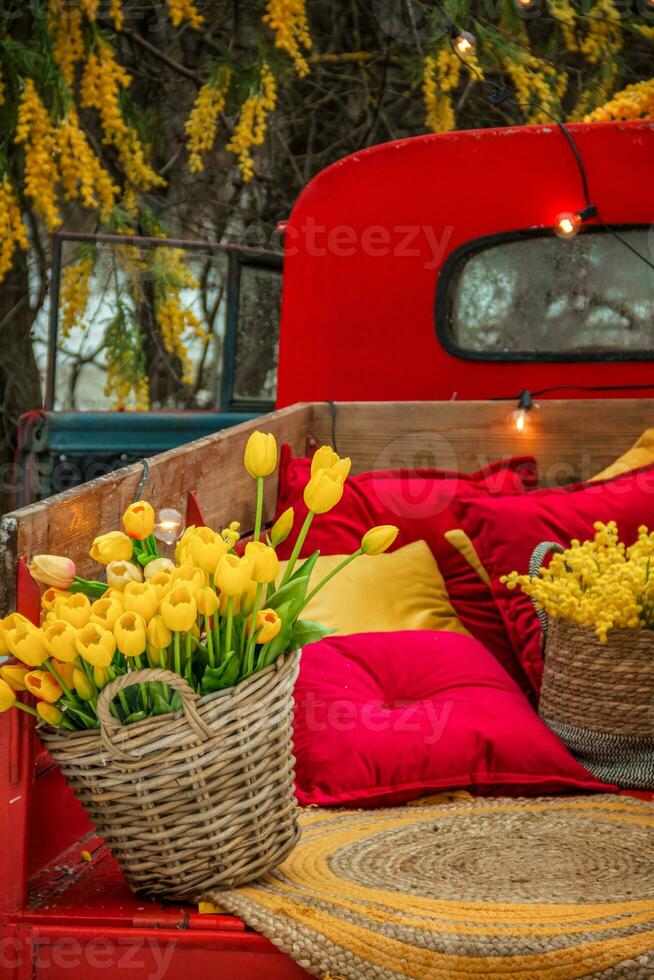 korg- korg med skön blommor. tulpaner, mimosor. en ljus röd lastbil tog med en massa av blommor. foto