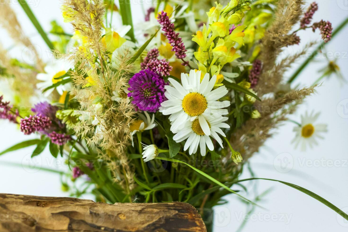 en torr stubbe, träd bark och en bukett av vild blommor i en små glas vas. eleganta utseende, layout, personlighet. foto