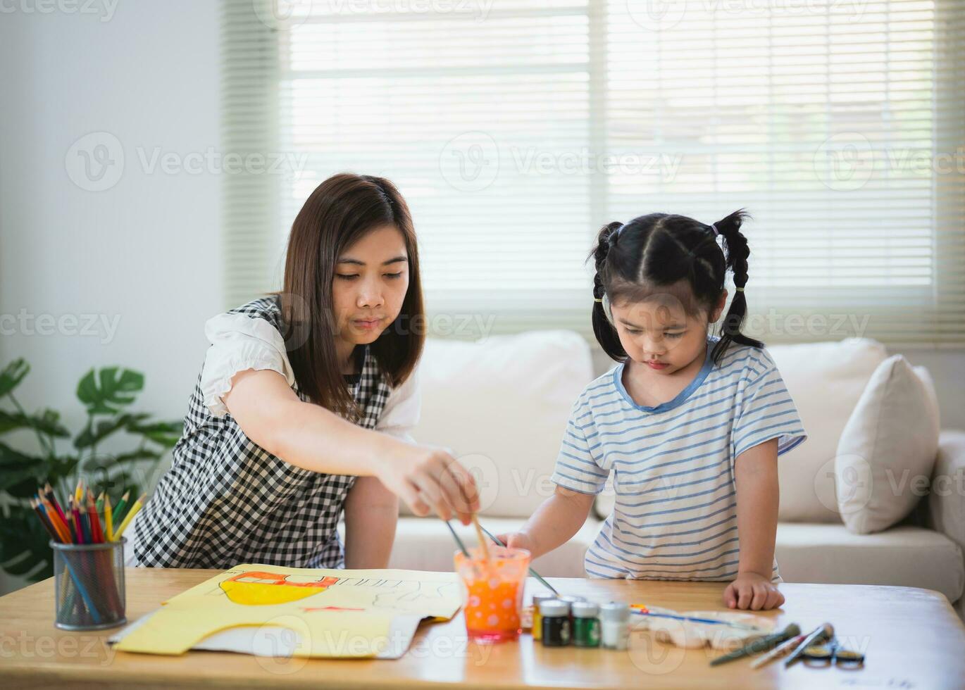 söt liten barn målning med färgrik färger. asiatisk flicka och mor använder sig av krita teckning Färg. dotter och mamma håller på med läxa färg tecknad serie tecken. bebis konstnär aktivitet livsstil begrepp. foto