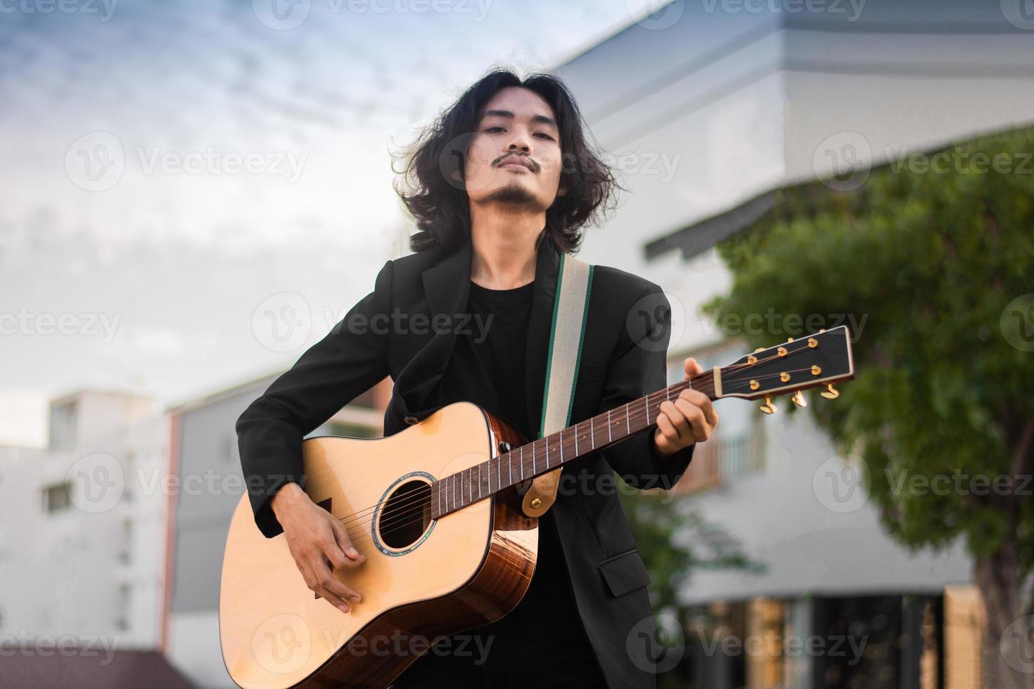 porträtt man håller gitarr spelar musikfestival utomhus, livsstil mode musikgata utomhus foto