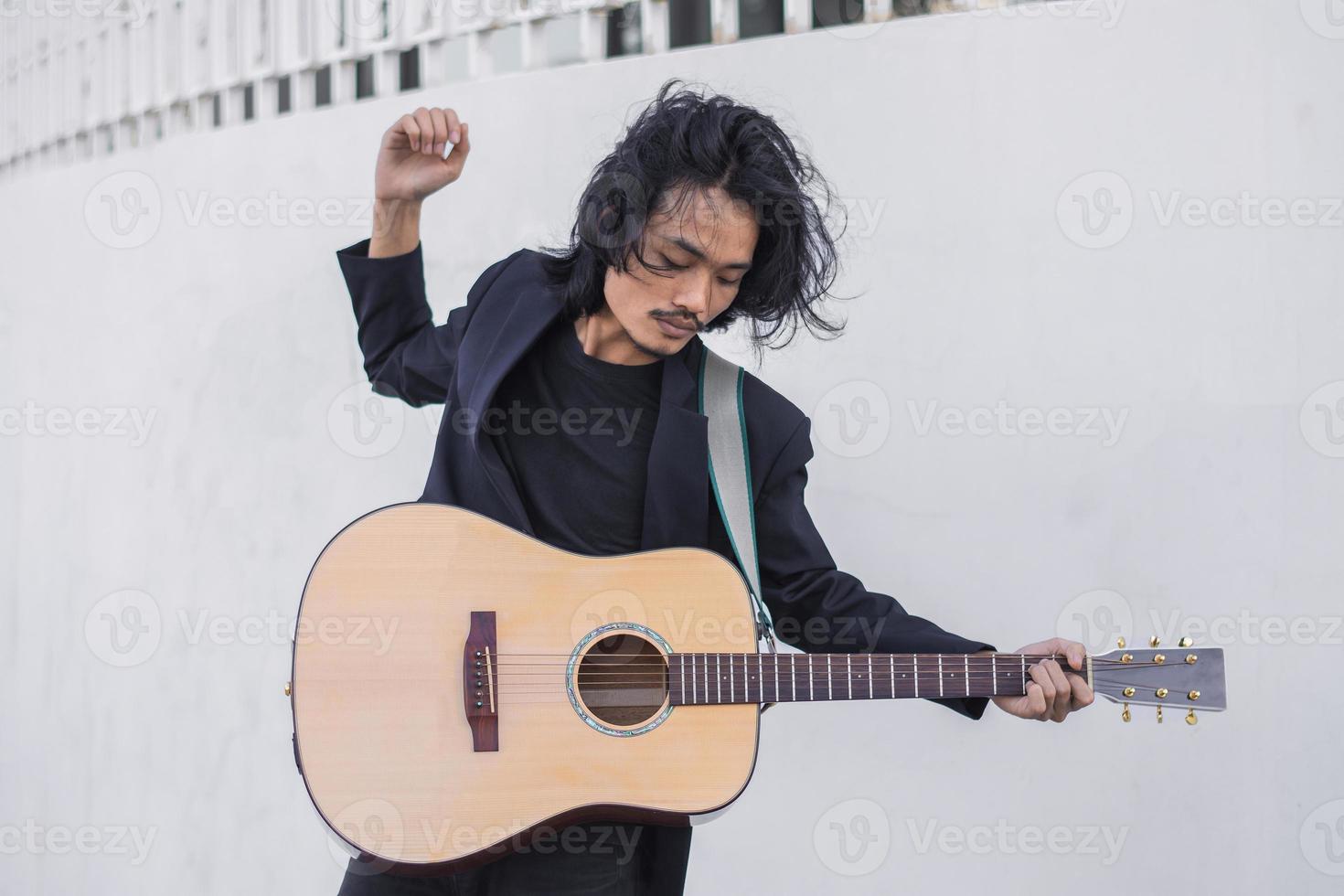 porträtt man håller gitarr spelar musikfestival utomhus, livsstil mode musikgata utomhus foto