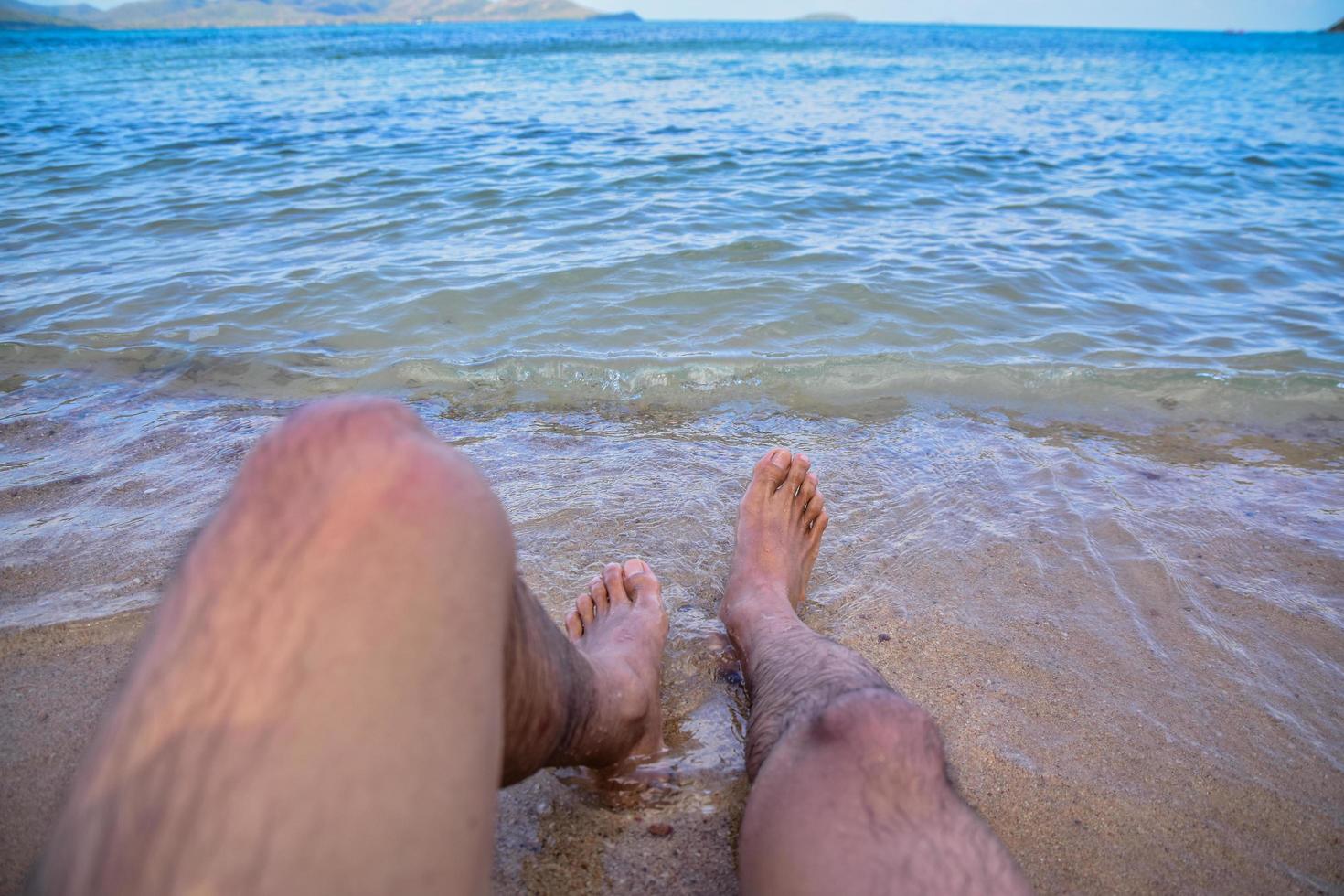 mannen är på stranden och fötterna i havet foto