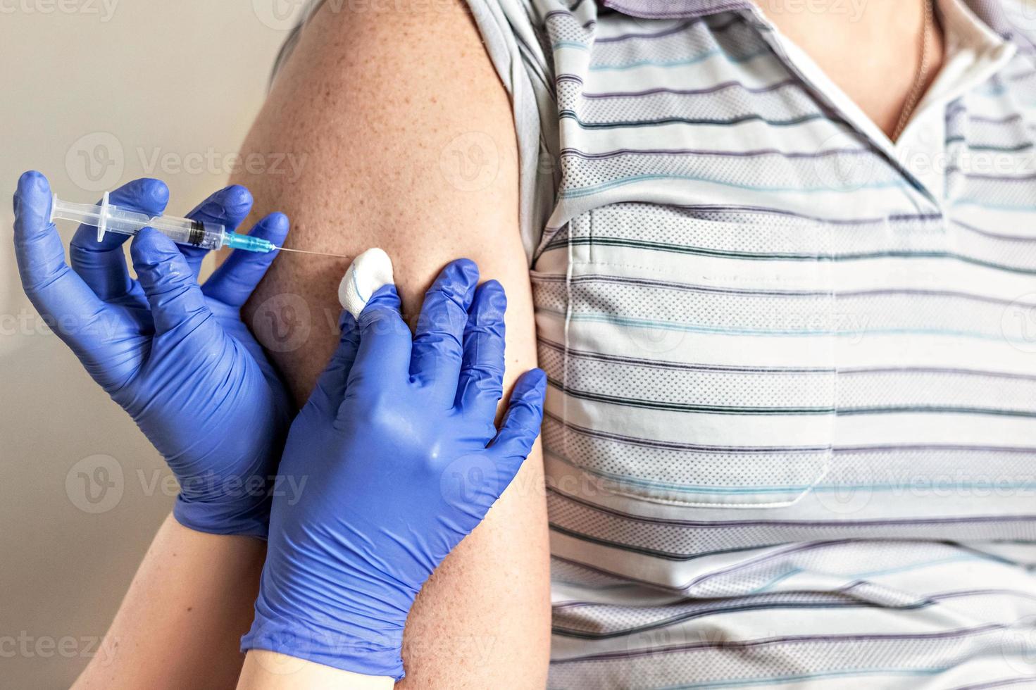 en läkare vaccinerar en man mot koronavirus på en klinik. närbild. begreppet vaccination, immunisering, förebyggande mot covid-19. foto