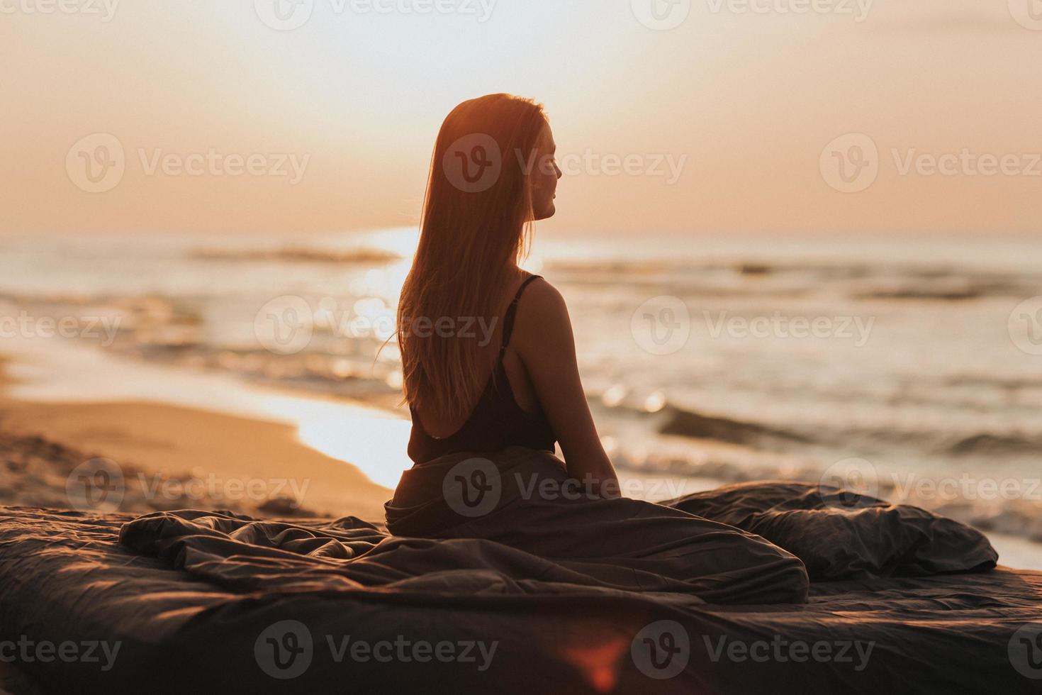 härlig morgonsoluppgång till sjöss, silhuett av flickan vid solnedgången. kvinna kopplar av vid havet. meditationskoncept foto