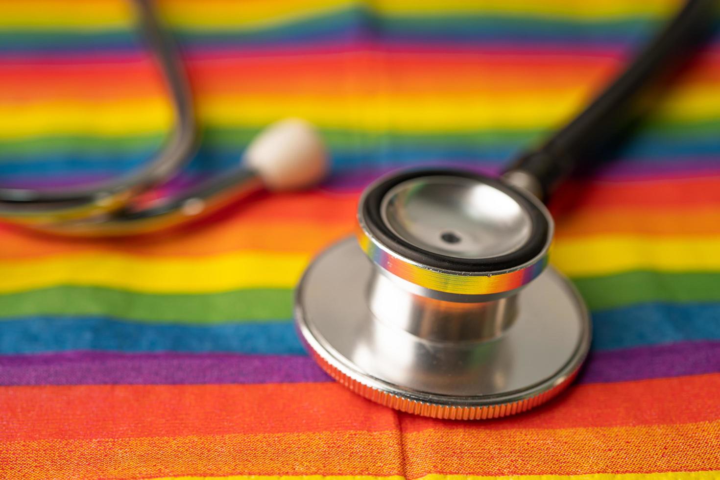 svart stetoskop på regnbågsflaggabakgrund, symbol för HBT stolthet månad firar årliga i juni sociala, symbol för homosexuella, lesbiska, bisexuella, transpersoner, mänskliga rättigheter och fred. foto