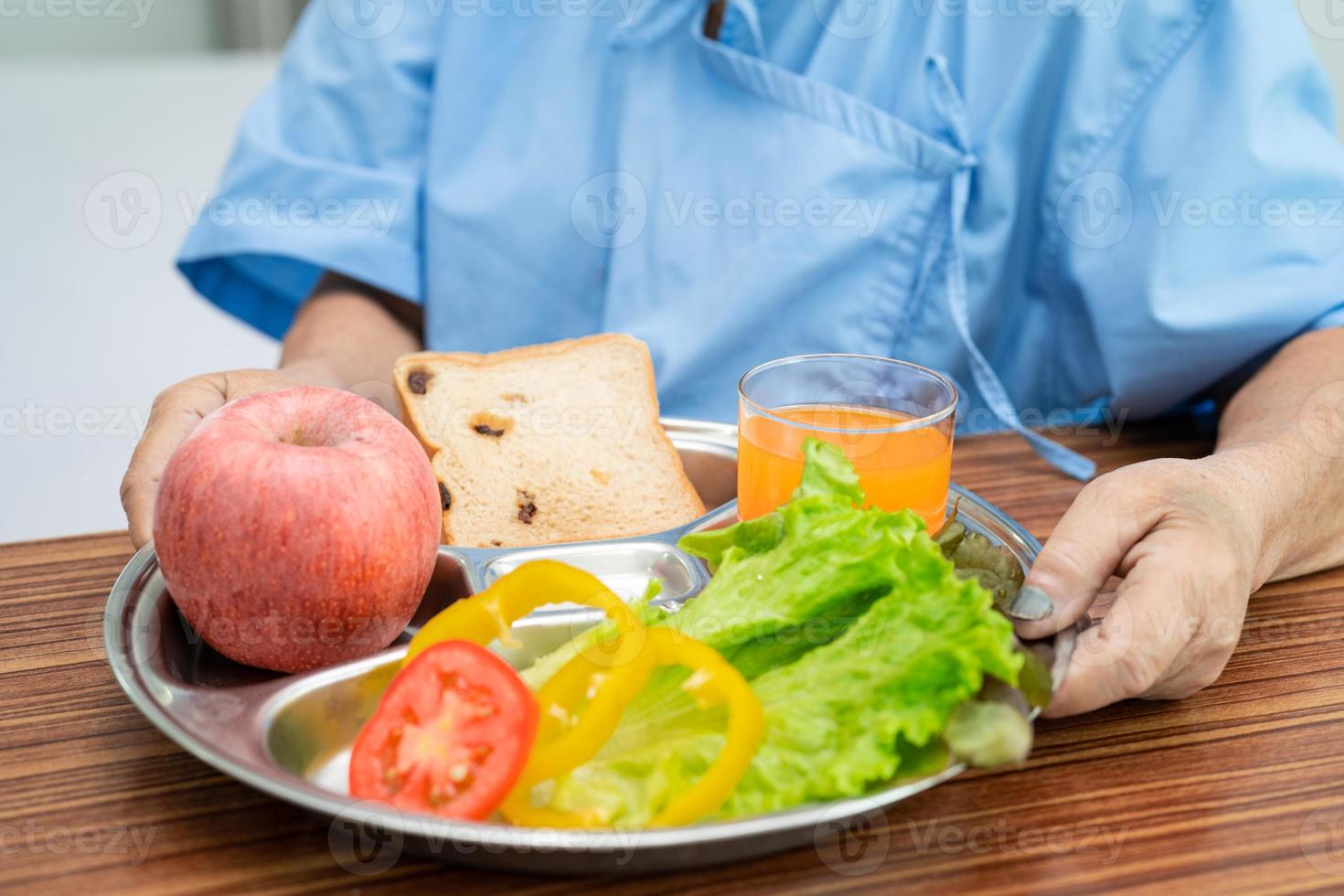 asiatisk senior eller äldre gammal damkvinna som äter frukost vegetabilisk hälsosam mat med hopp och lycklig medan du sitter och är hungrig på sängen på sjukhus. foto