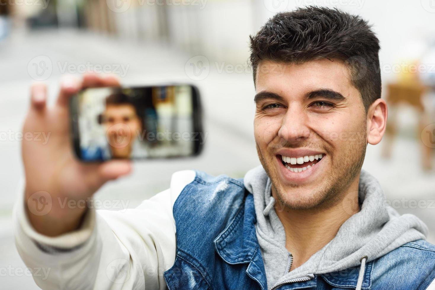 ung manselfie i stadsbakgrund med en smartphone foto