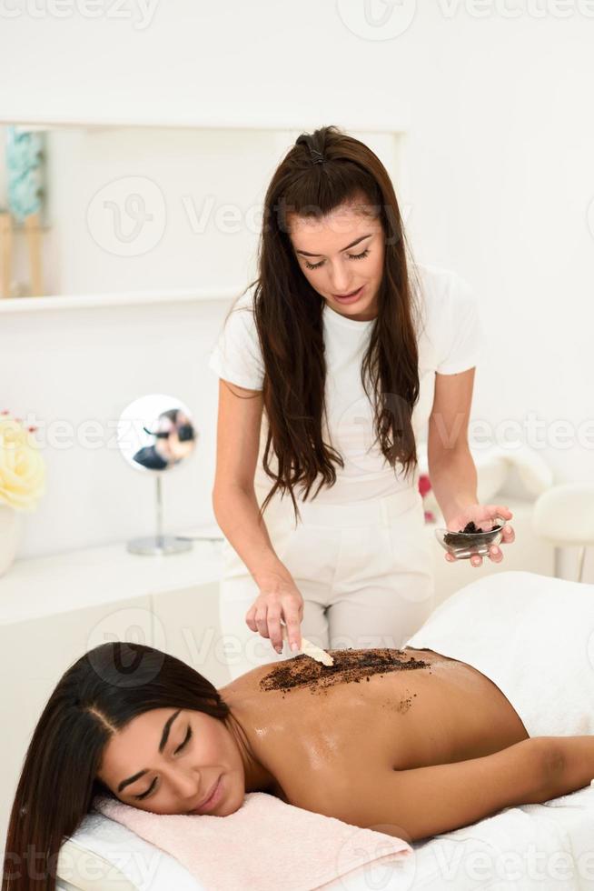 kvinna rengör kroppens hud med kaffeskur i spa-hälsocentret. foto