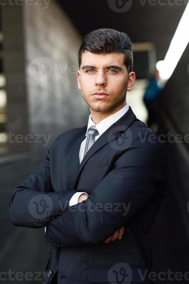 ung affärsman nära en kontorsbyggnad som bär svart kostym foto