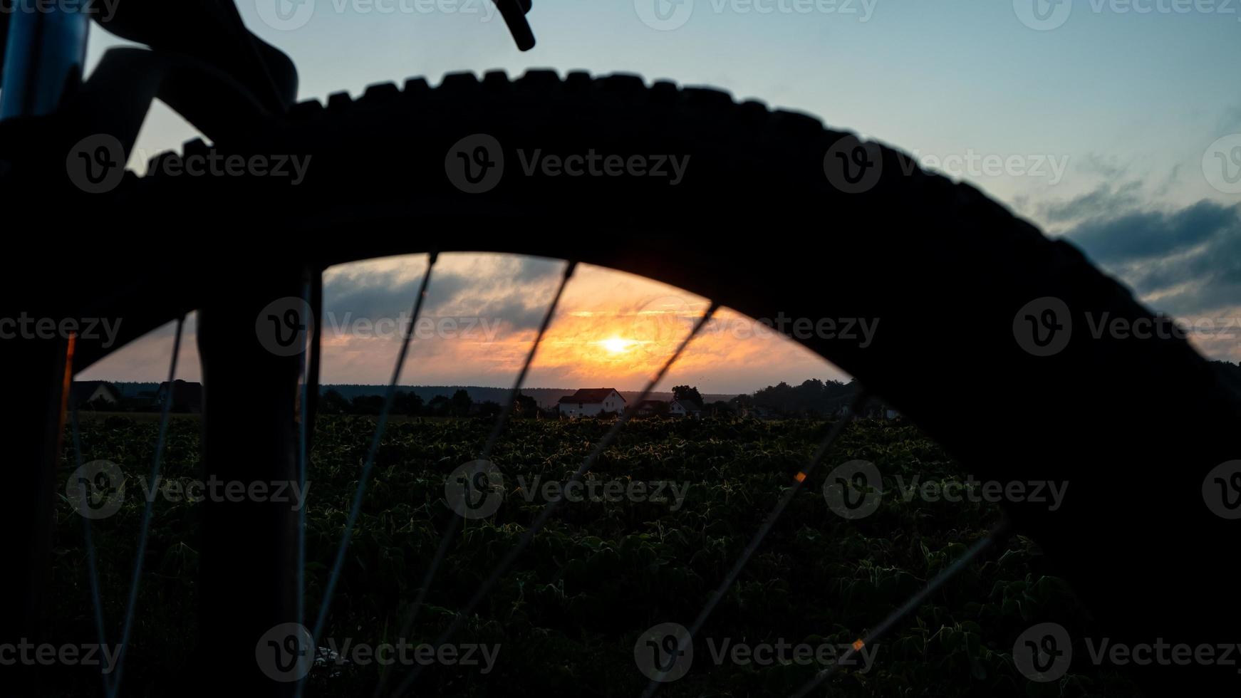 cykelturism kvällssolnedgång, orange sol på en silhuett cykel hjul bakgrund foto