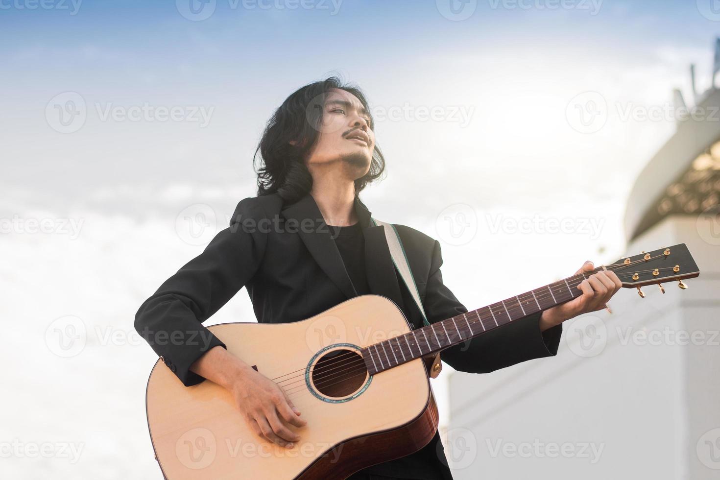 man sjunger sång och spelar gitarr utomhus foto