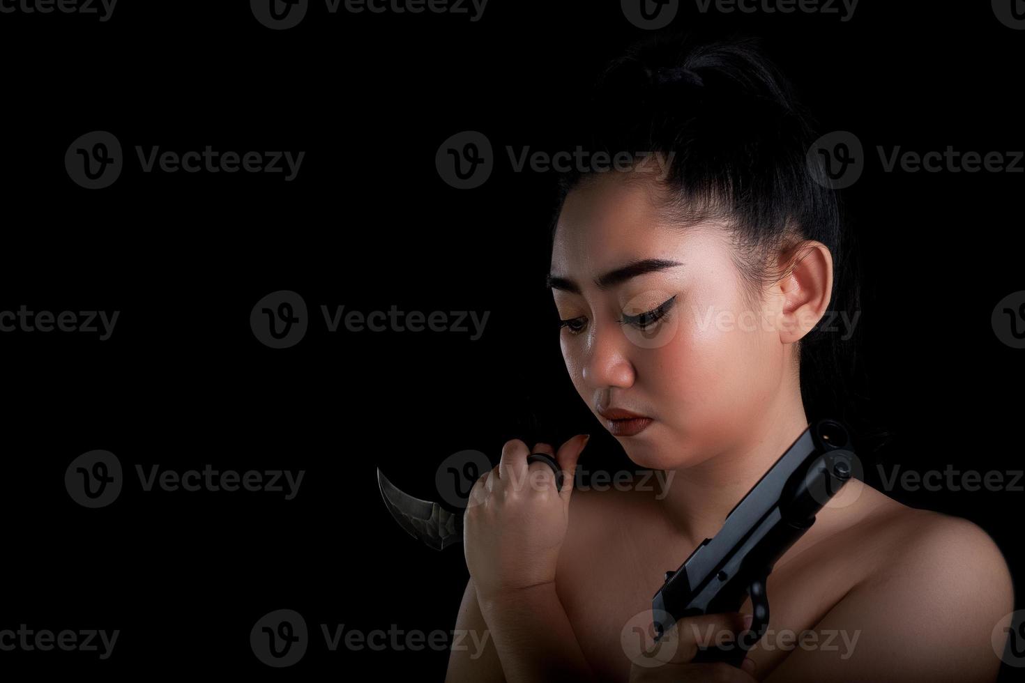 asien kvinna en hand som håller en pistol och karambitkniv på den svarta bakgrunden foto