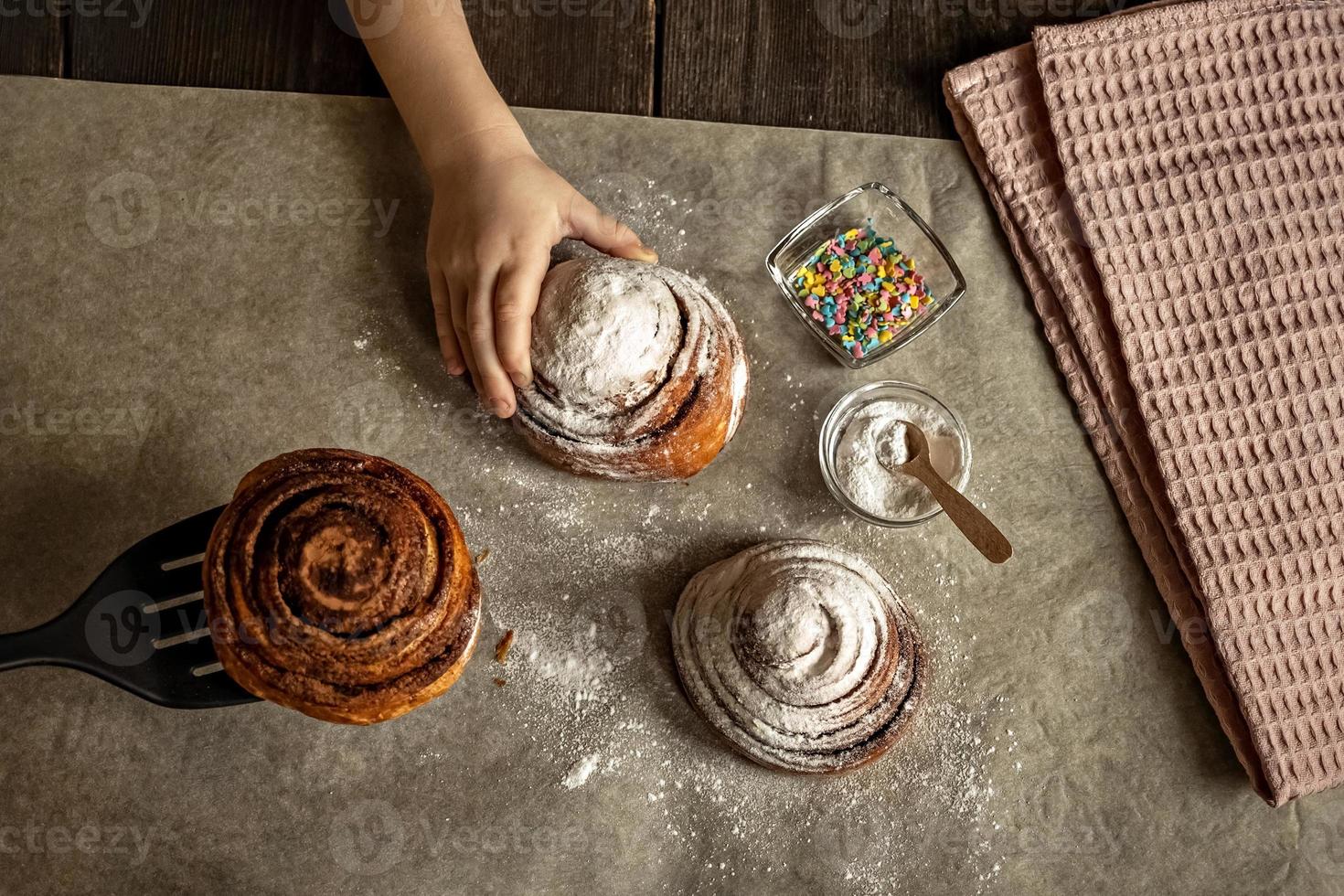 barns hand tar en nybakad kanelbulle foto