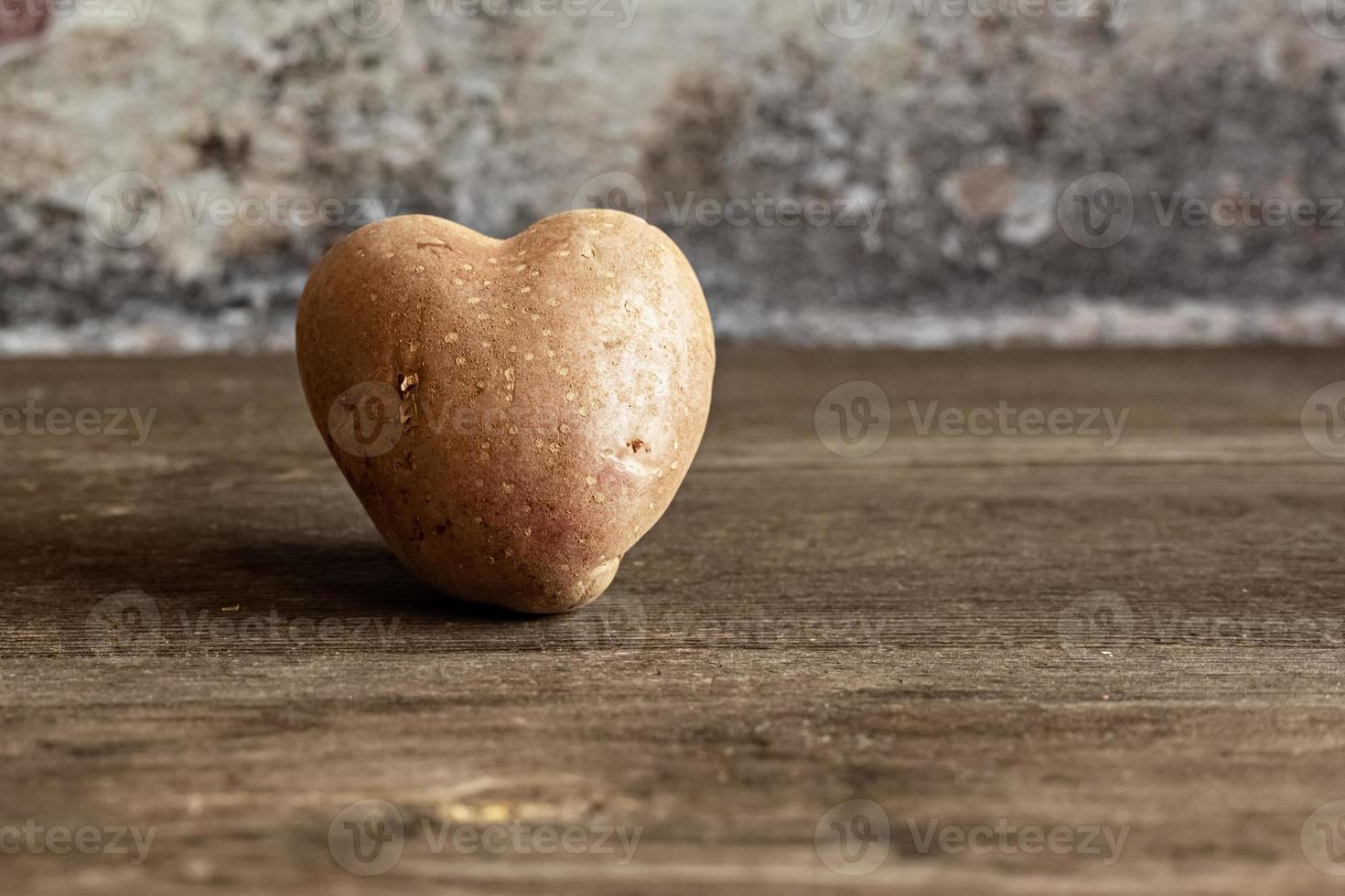 hjärtformad röd potatis på vintage bakgrund. begreppet jordbruk, skörd, vegetarism. alla hjärtans dag. fyrkantig, ful mat. foto