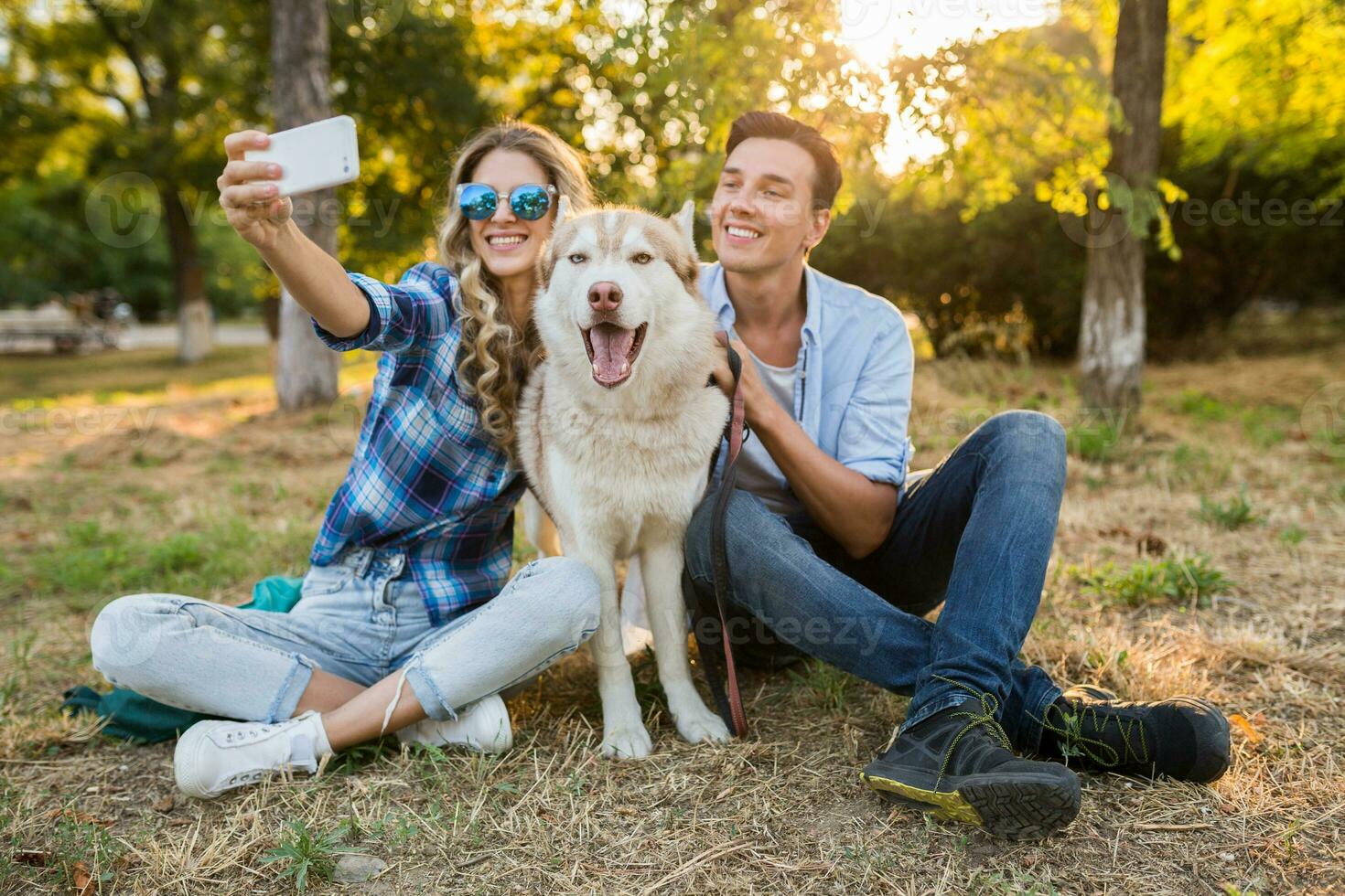 solig ung eleganta par spelar med hund i parkera foto