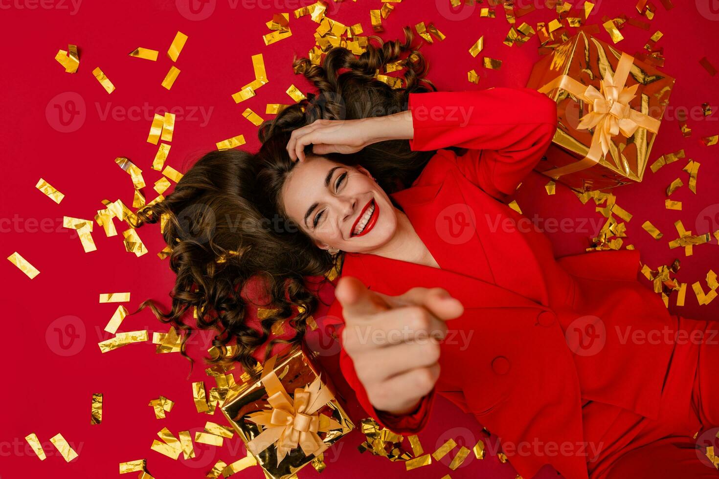 attraktiv kvinna fira jul på röd bakgrund i konfetti foto