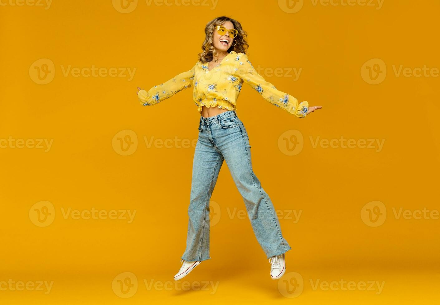 eleganta Lycklig leende blond kvinna Framställ i jeans på gul bakgrund foto