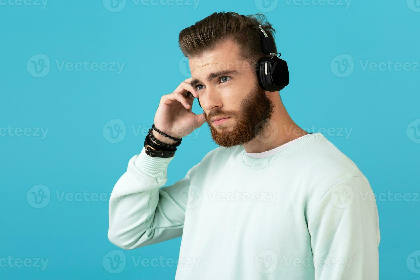 eleganta ung man lyssnande till musik på trådlös hörlurar foto