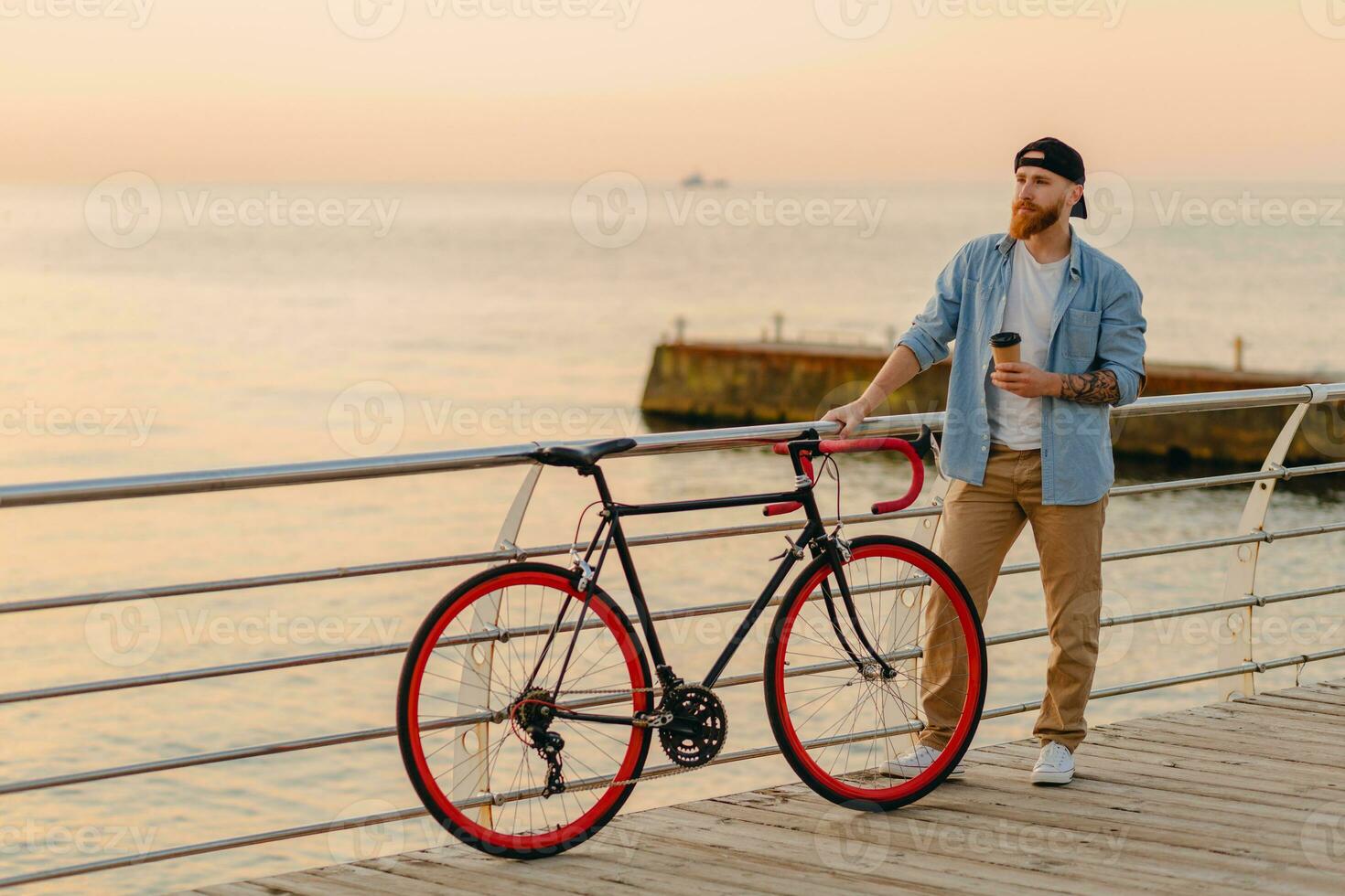 stilig skäggig man reser med cykel i morgon- soluppgång förbi de hav foto