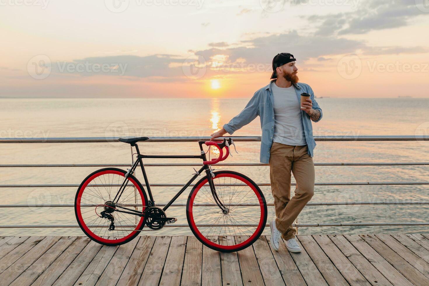 stilig skäggig man reser med cykel i morgon- soluppgång förbi de hav foto