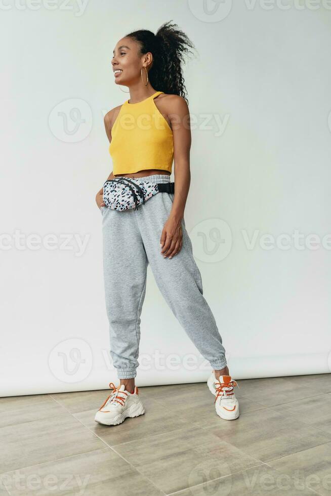 attraktiv svart afrikansk amerikan kvinna Framställ i eleganta hipster utrusta på vit bakgrund foto