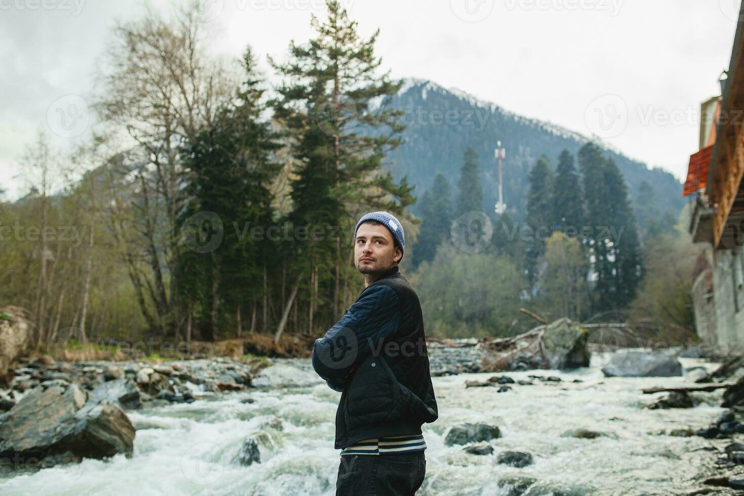 ung hipster man gående på en sten på flod i vinter- skog foto