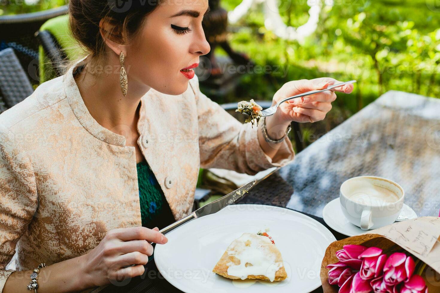 ung eleganta kvinna Sammanträde i Kafé, äter gott kaka foto