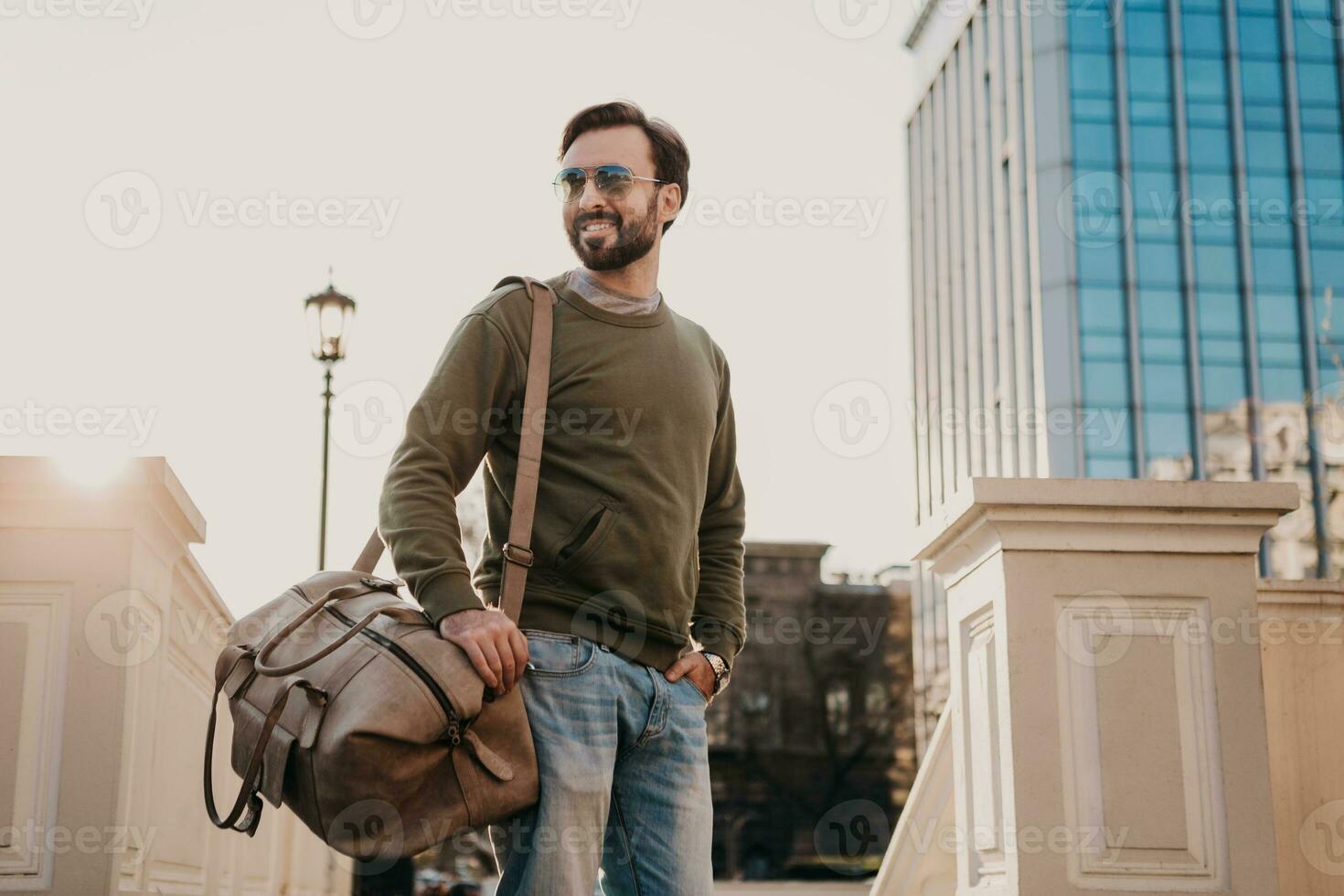 hipster man gående i gata med väska foto