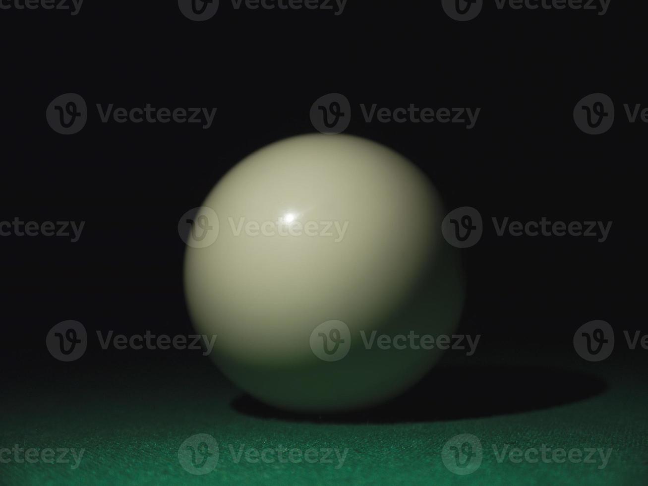 vit boll på ett biljardbord i mörkret foto