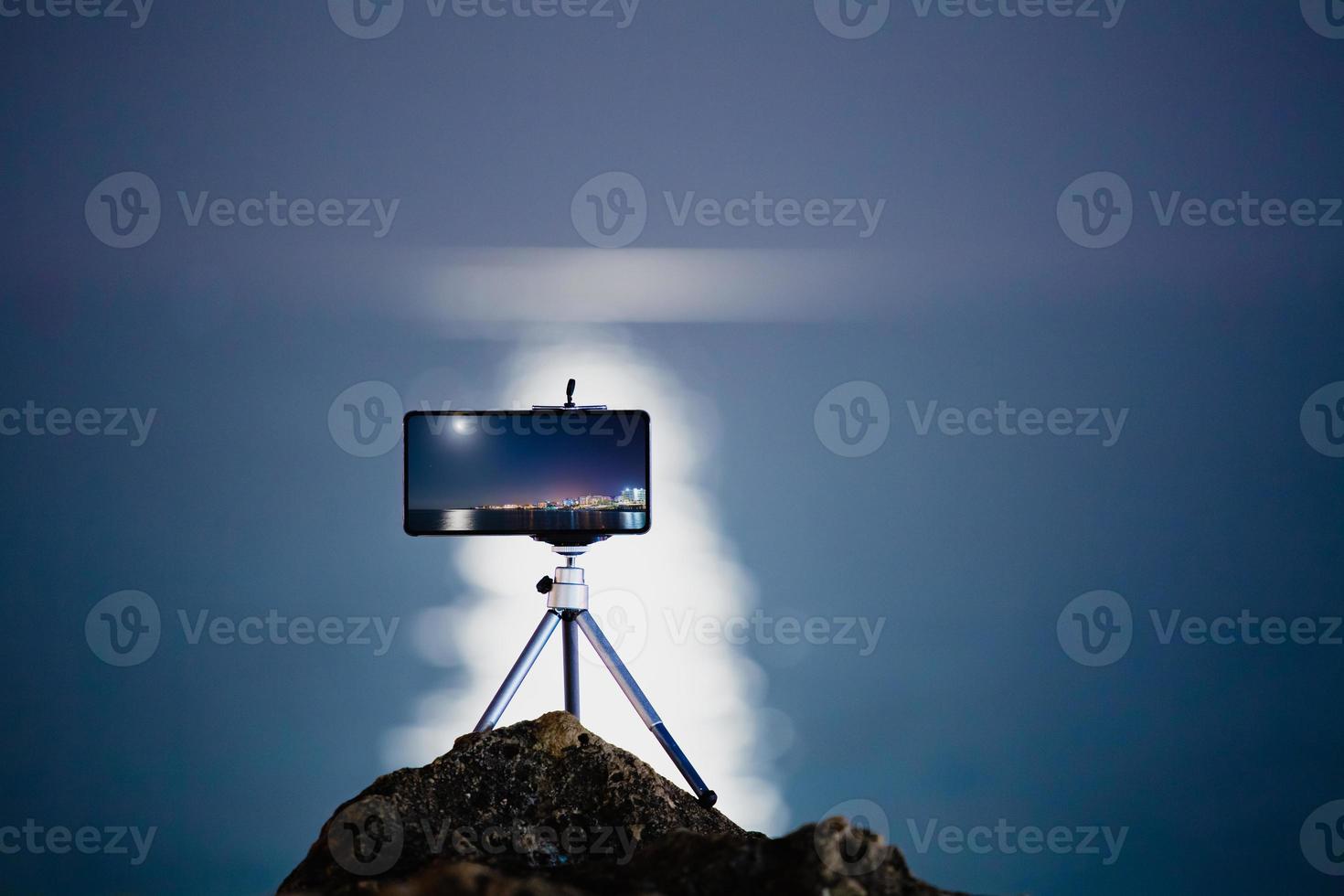 använder en smartphone på ett stativ med lång exponering av havet på natten foto