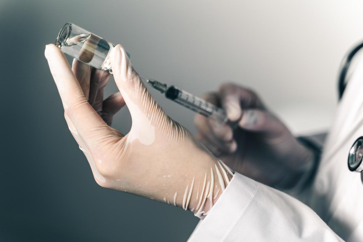 läkaren som håller en spruta med covid-19-vacciner i glasflaska. covid-19 koronavirusbehandlingskoncept. foto