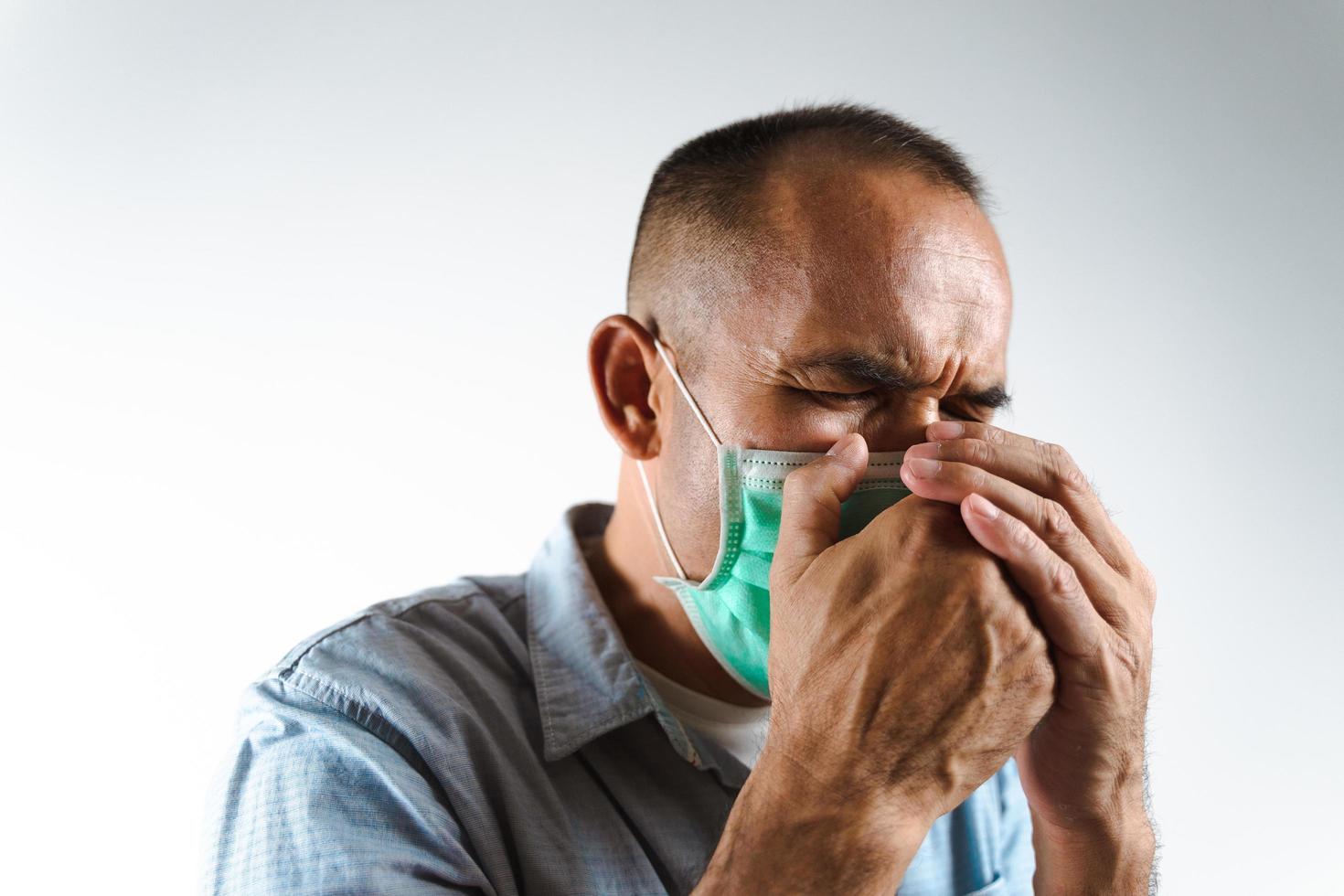 man som bär ansiktsmask som nyser eller hostar över handen för att förhindra spridning av viruset covid-19 eller koronavirus på vit bakgrund. foto
