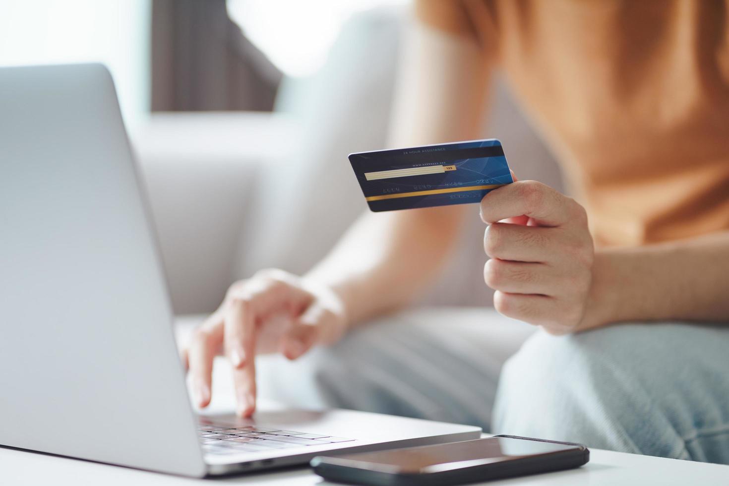 ung kvinna med kreditkort och använder bärbar dator. online shopping, internetbank, e-handel, spendera pengar, arbeta hemifrån koncept foto