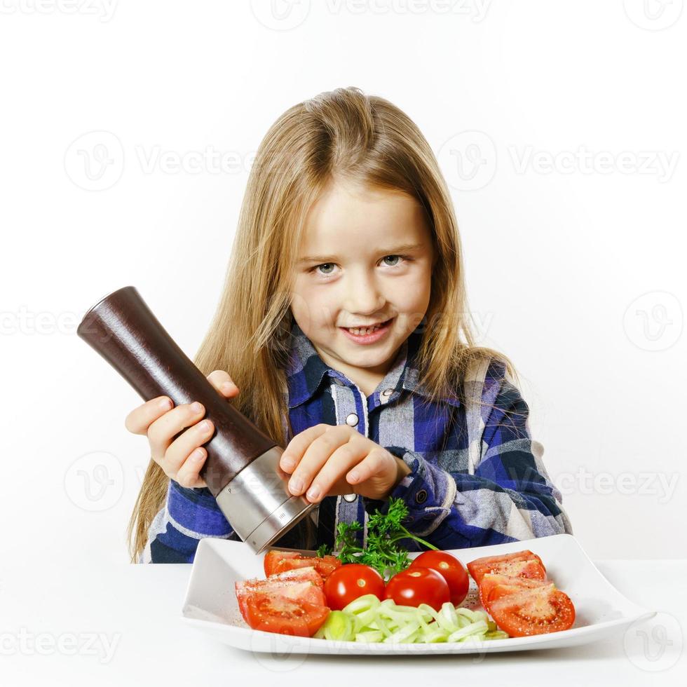 söt liten flicka med sallad och pepparask foto