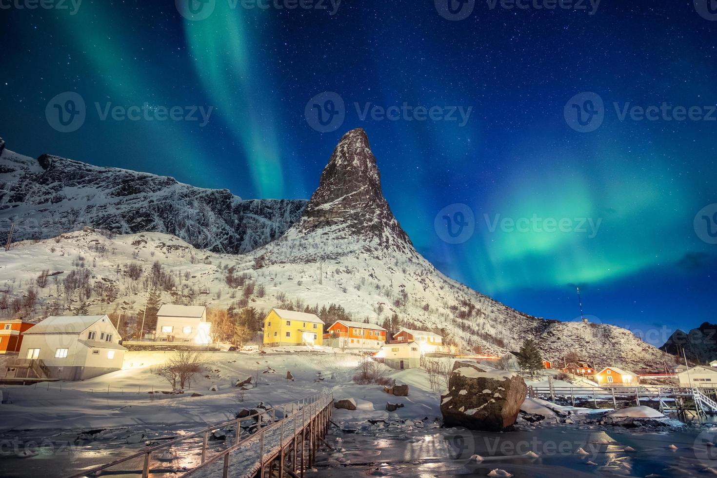 färgglad skandinavisk by med norrsken över toppberg vid lofoten foto