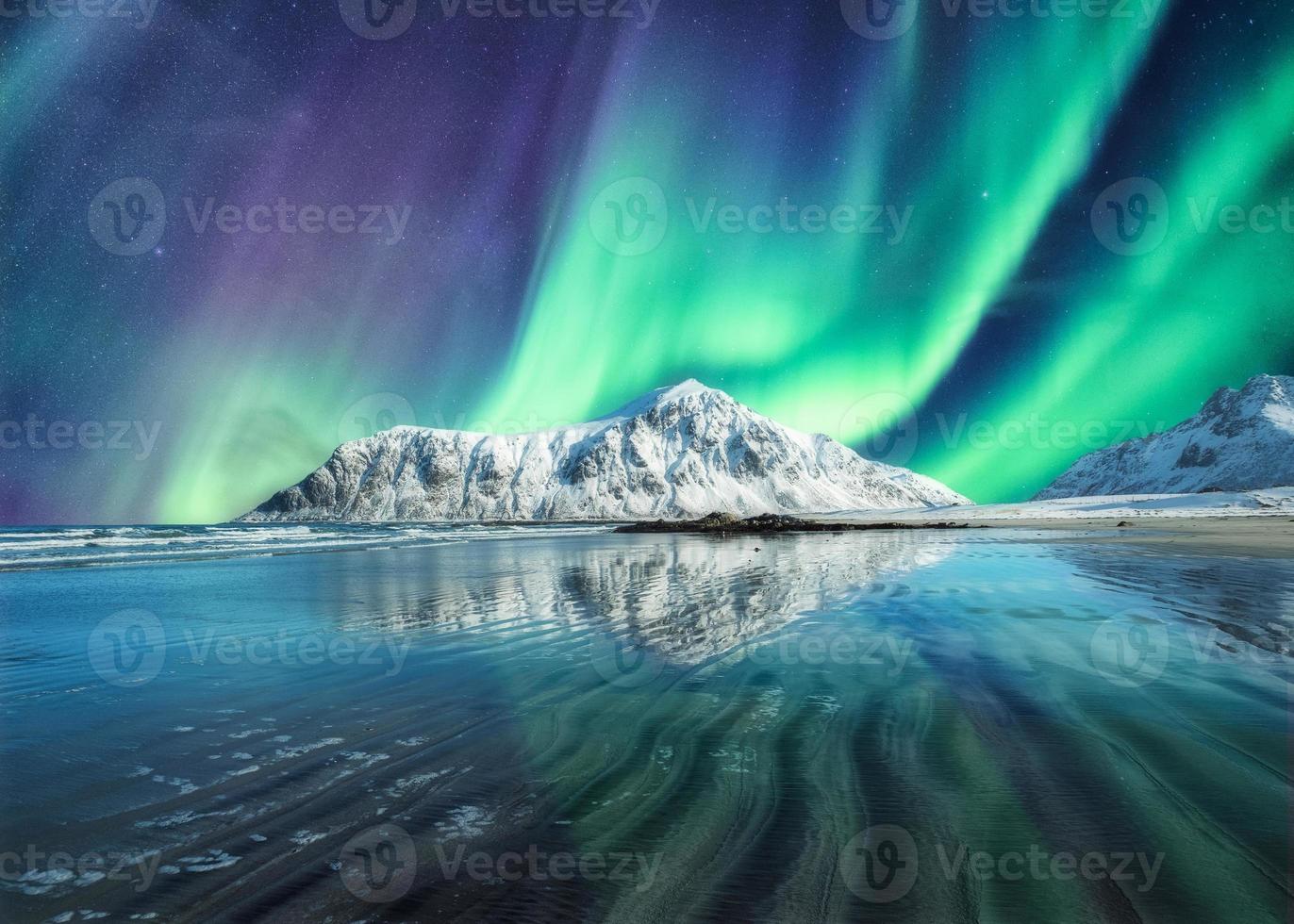 aurora borealis, norrsken ovan på snöiga berg i skagsanden beach på lofoten öarna foto