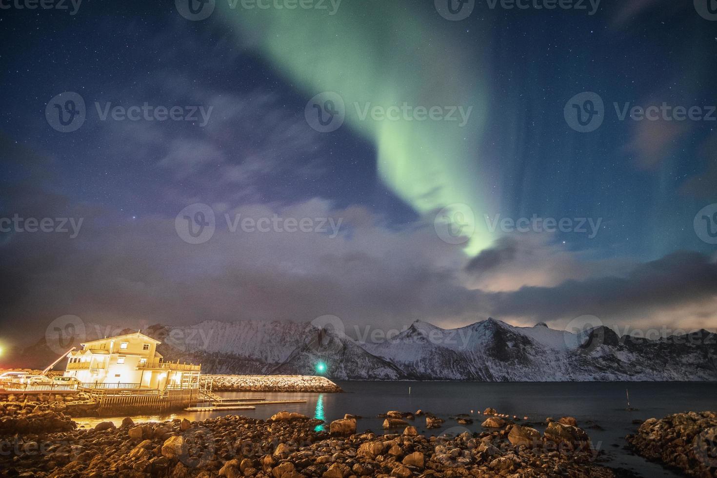 aurora borealis på snöiga berg med ljus hus foto