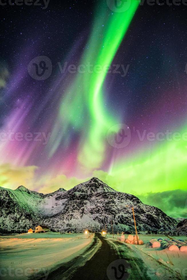 aurora borealis norrsken explosion över berg och lantlig väg foto