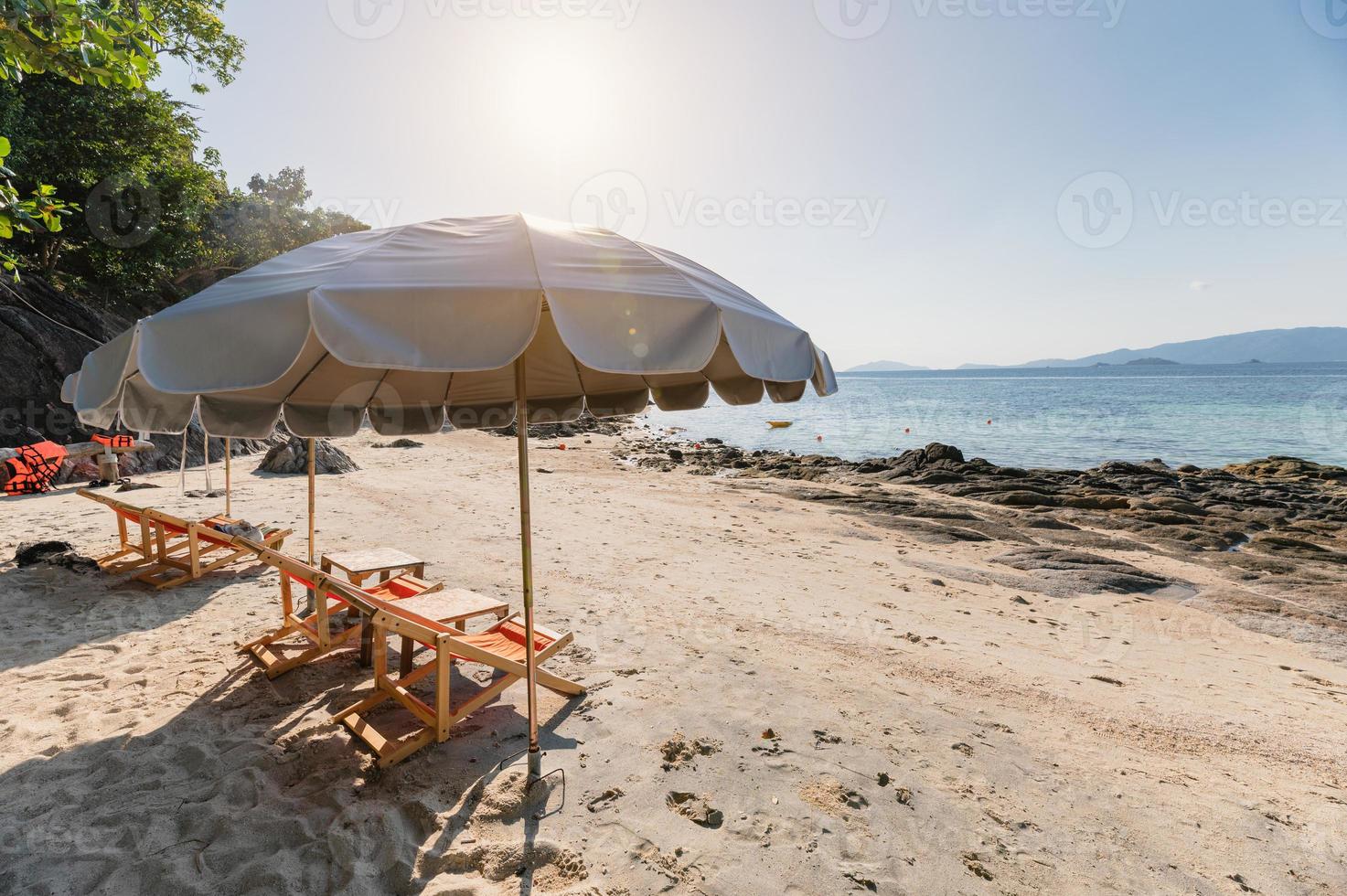 paraply med solsäng av trä på den vita stranden vid det tropiska havet foto