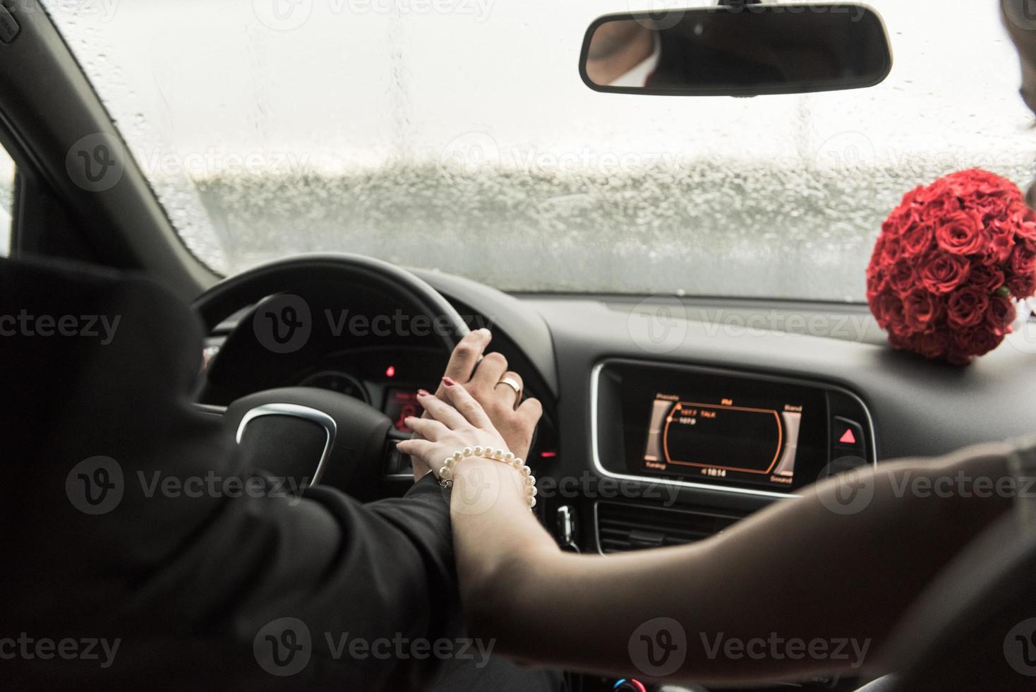 bruden och brudgummen i regnet täckt i bilen foto