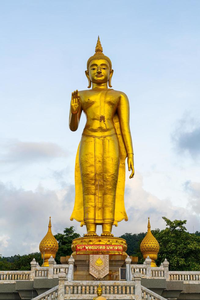 en gyllene buddha staty med himmel på bergstoppen vid hat yai kommunens offentliga park, Songkhla-provinsen, Thailand foto