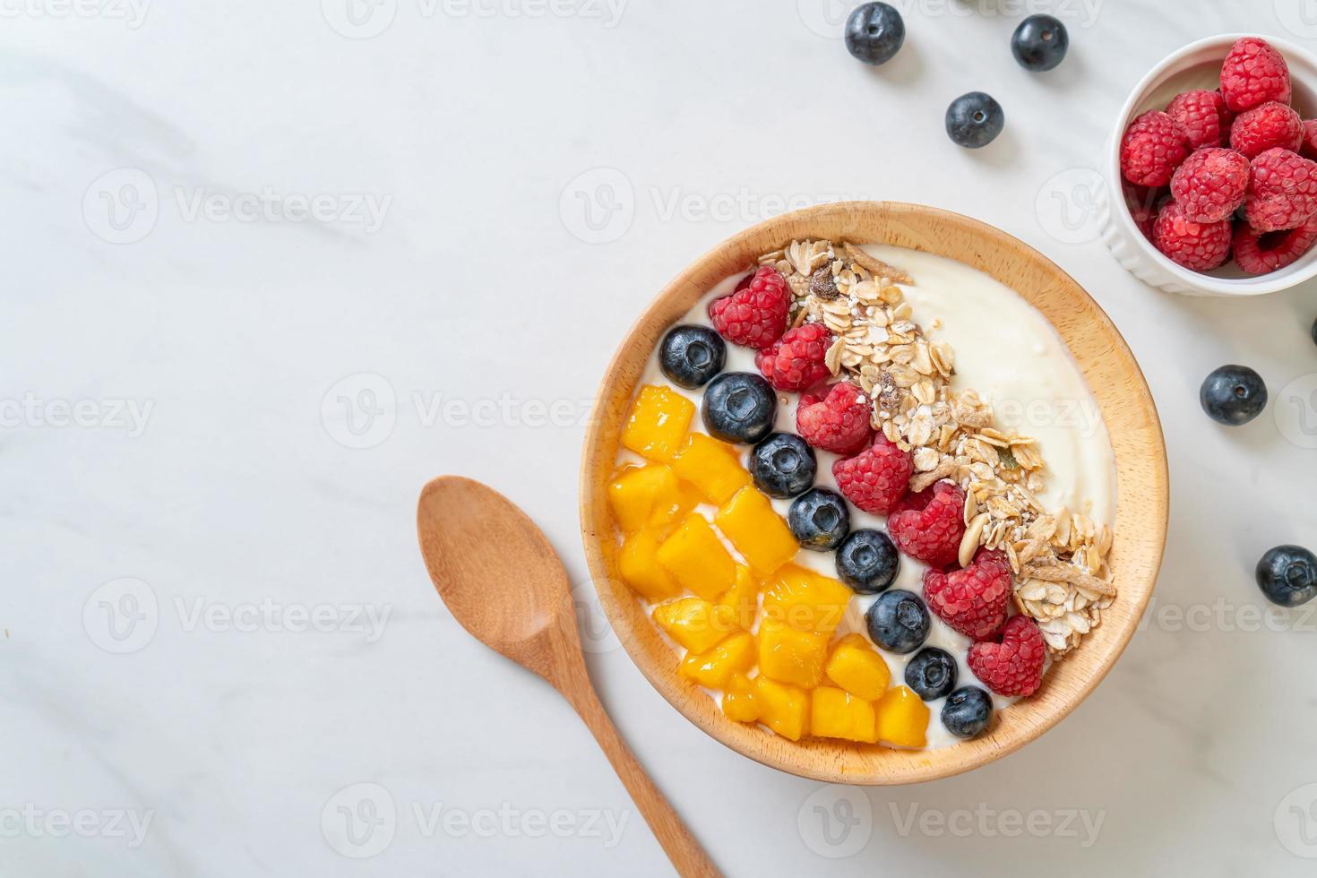 hemlagad yoghurtskål med hallon, blåbär, mango och granola - hälsosam matstil foto