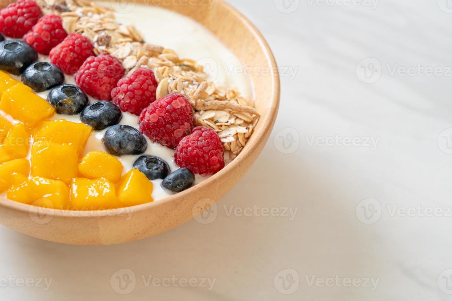 hemlagad yoghurtskål med hallon, blåbär, mango och granola - hälsosam matstil foto