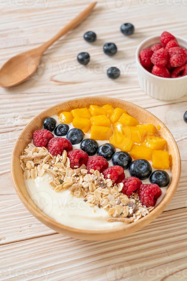 hemlagad yoghurtskål med hallon, blåbär, mango och granola - hälsosam matstil foto