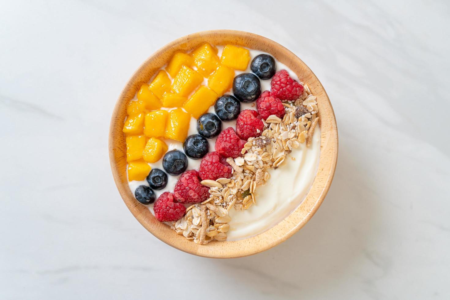 hemlagad yoghurtskål med hallon, blåbär, mango och granola - hälsosam matstil foto