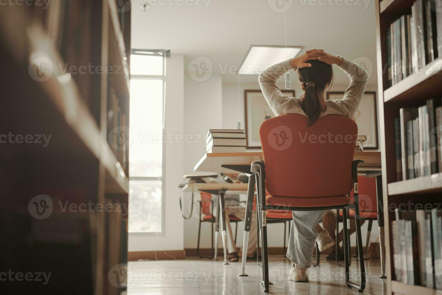 asiatisk studerande kvinna läsa böcker i bibliotek på universitet. ung flicka påfrestning trött ha problem medan studie hård. sorg begrepp foto