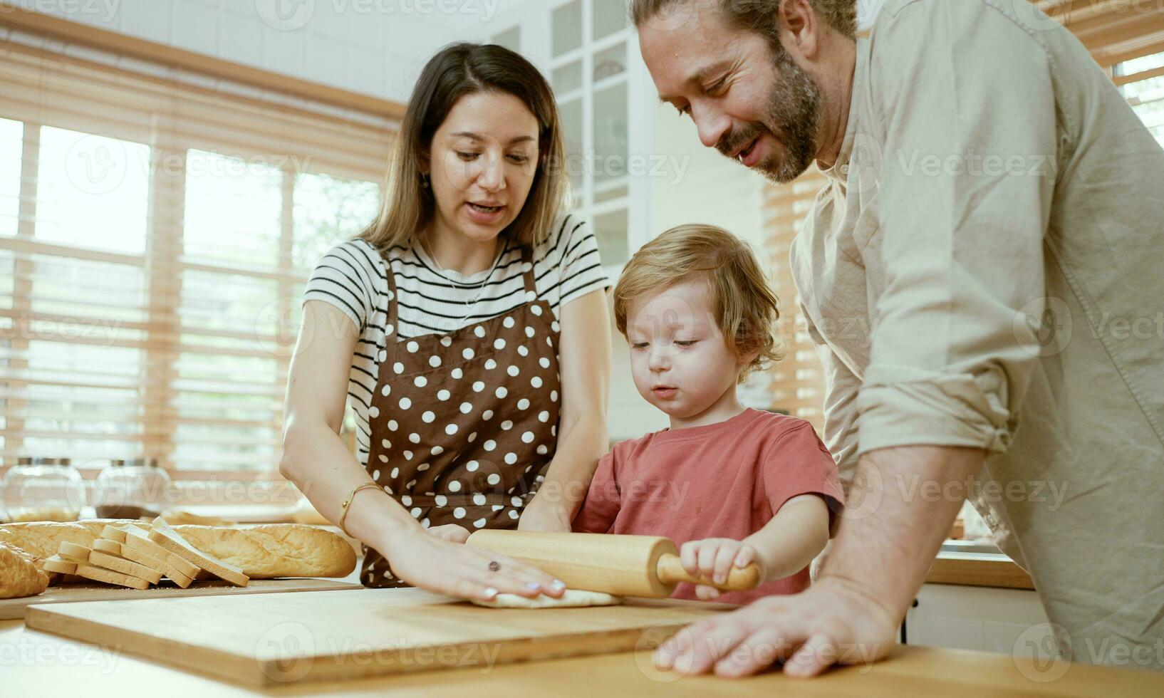 far och mor undervisning bebis son knådning deg på kök disken på Hem. föräldrar och pojke unge njut av och roligt inomhus aktivitet matlagning tillsammans. foto