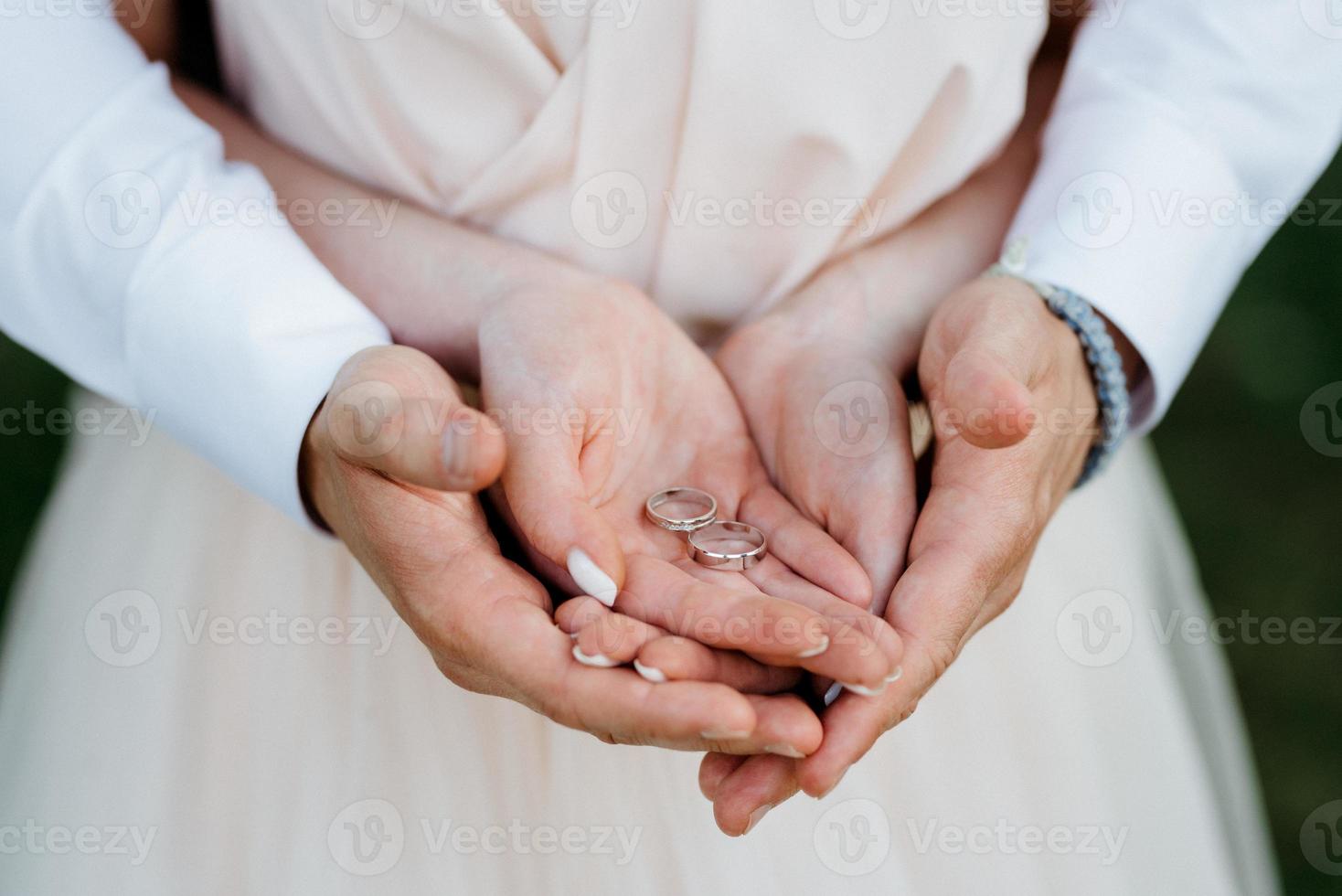 bruden och brudgummen höll händer med vigselringar foto